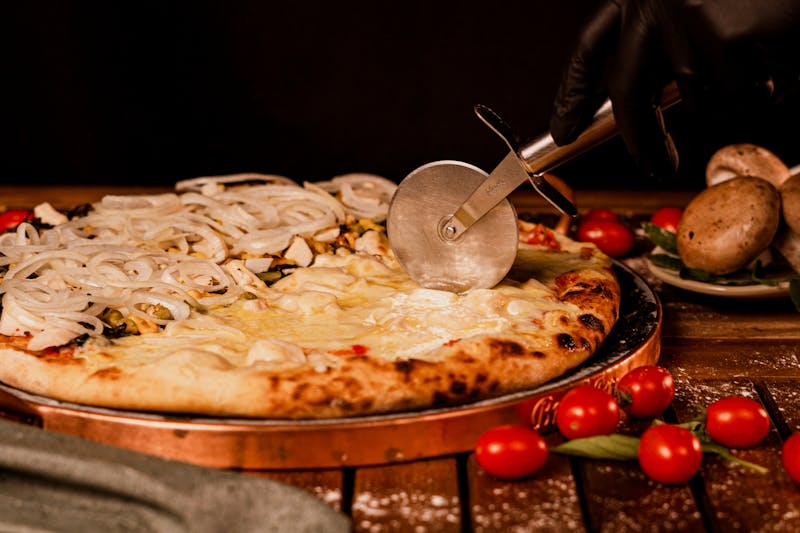Homemade pizza dough being stretched by hand on a floured surface